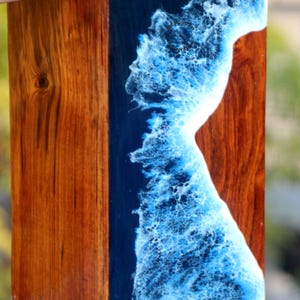 Może przedstawiać: Prostokątna drewniana skrzynka z wkładką z niebieskiej i białej żywicy. Żywica ma falisty wzór przypominający fale oceanu.