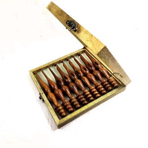 May include: A set of eight wooden crochet hooks in a wooden box with a latch. The hooks are different sizes and have a brown finish. The box is labeled "WOOD ART".