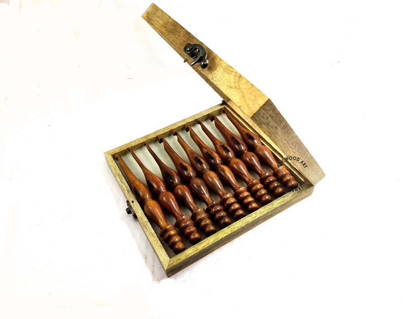 May include: A set of eight wooden crochet hooks in a wooden box with a latch. The hooks are different sizes and have a brown finish. The box is labeled "WOOD ART".
