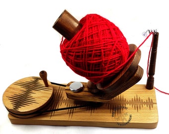 May include: Wooden yarn ball winder with a red yarn ball on the winder. The winder has a crank and a base with the words "National Art International" engraved on it.