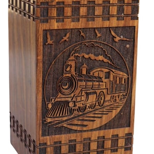 Peut inclure: Une boîte en bois avec un motif gravé d'un train à vapeur sur le devant. La boîte est brune et a un grain de bois foncé. Le train est dans un cercle avec des oiseaux qui volent au-dessus.