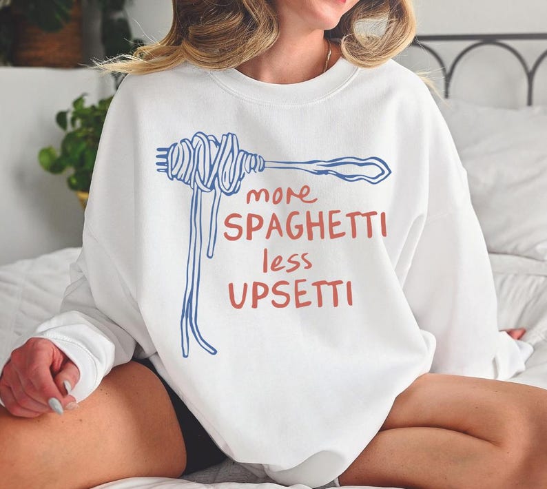 May include: White sweatshirt with a blue and red graphic of a fork with spaghetti and the text "more spaghetti less upsetti".