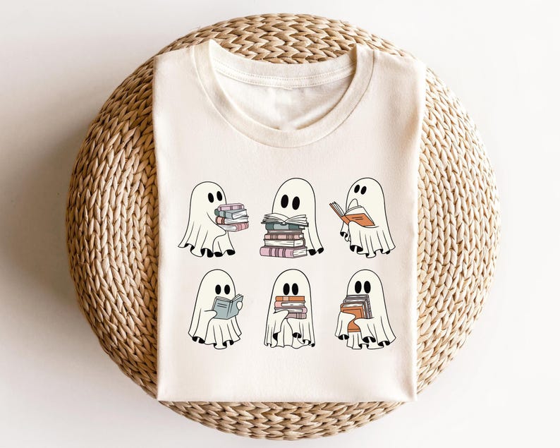 May include: A white t-shirt with a design of six ghosts holding or reading books. The ghosts are all different sizes and have different expressions. The text "Bookish Ghosts" is printed on the shirt.