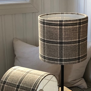 May include: Two black table lamps with brown and white checked lampshades. The lampshades are made of a textured fabric.