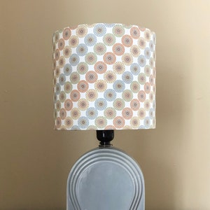 May include: A gray ceramic table lamp with a geometric design. The lampshade is white with a pattern of colorful circles.
