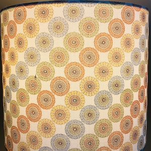May include: A white lampshade with a pattern of brown, blue, and yellow circles. The circles have a mandala-like design.