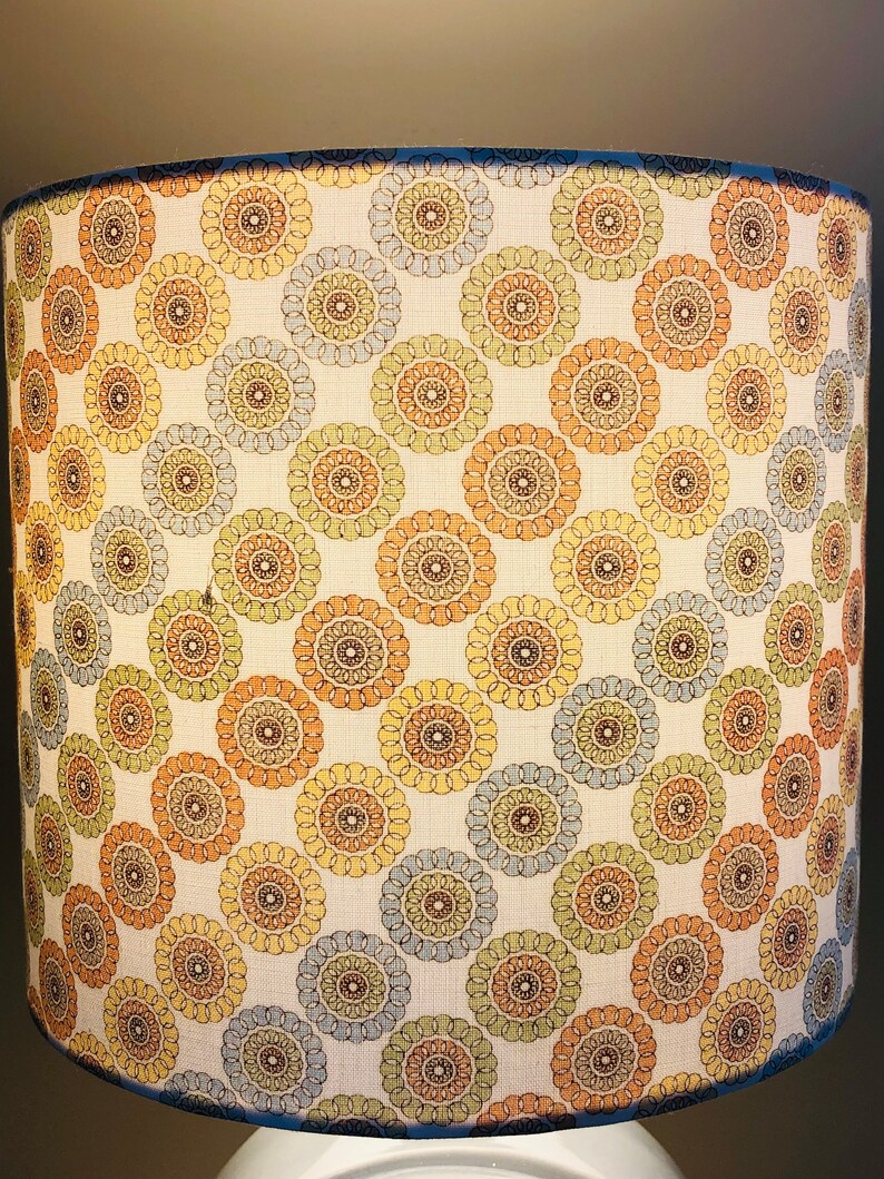 May include: A white lampshade with a pattern of brown, blue, and yellow circles. The circles have a mandala-like design.