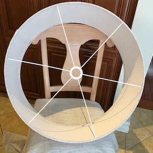 May include: A white lampshade with a white wire frame. The lampshade is round and has a white fabric covering.