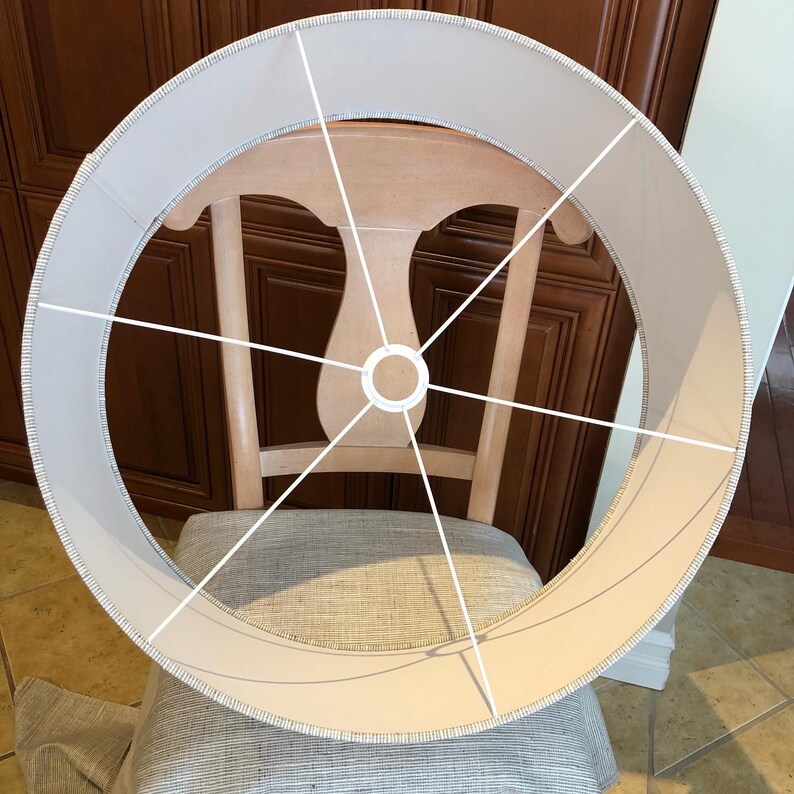 May include: A white lampshade with a white wire frame. The lampshade is round and has a white fabric covering.