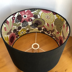 May include: Black lampshade with a floral print lining. The print features pink, green and brown flowers on a white background.