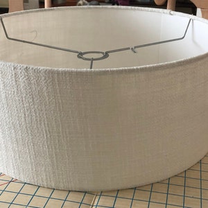 May include: A white drum lampshade with a textured fabric finish.