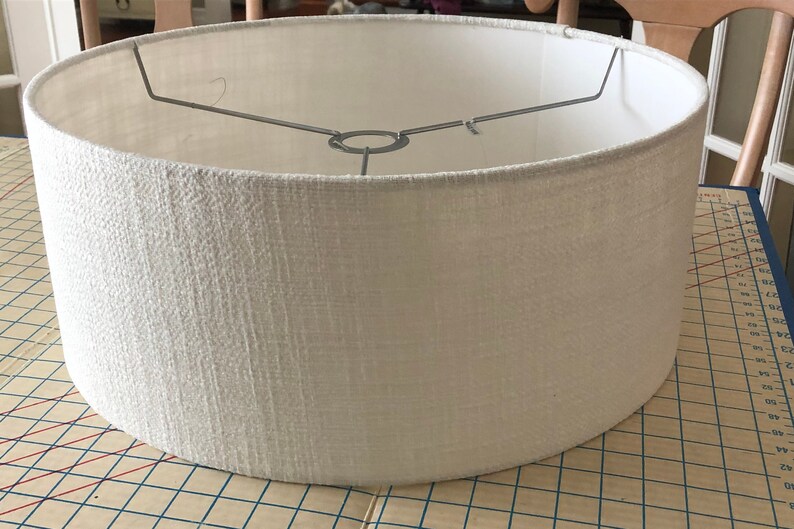 May include: A white drum lampshade with a textured fabric finish.