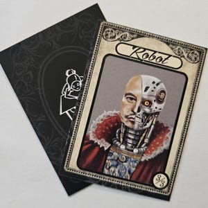 May include: A vintage-style card with a black frame and ornate gold accents. The card features a portrait of a person with a robotic half-face. The card reads "Robot" and "3/3".