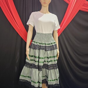 May include: A white short-sleeved top paired with a green and white checkered skirt. The skirt features black lace trim and green ribbon accents. A white head wrap completes the outfit, displayed on a mannequin.
