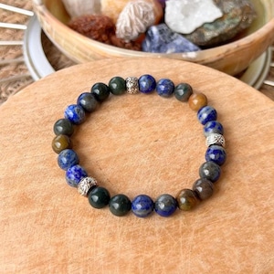 Peut inclure: Un bracelet en perles avec des pierres bleues, vertes et brunes et des accents argentés.