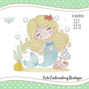 Può includere: Design ricamato di una sirena sorridente con capelli biondi, coda blu e un fiore tra i capelli. Il design include bolle, coralli e una conchiglia. Il testo "Cute Embroidery Boutique" è in basso.