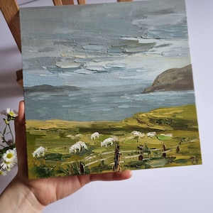 Pode incluir: Pintura a &oacute;leo de uma paisagem com ovelhas pastando num campo verde perto de um corpo de &aacute;gua sob um c&eacute;u nublado. A pintura tem um estilo texturizado, impasto, com pinceladas vis&iacute;veis. A paleta de cores inclui tons de verde, cinza e branco.