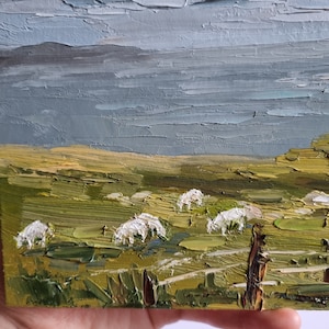 Pode incluir: Pintura a &oacute;leo em impasto de uma paisagem rural com ovelhas pastando num campo verde sob um c&eacute;u nublado. A obra de arte apresenta pinceladas texturizadas e uma paleta de verdes, azuis e amarelos.