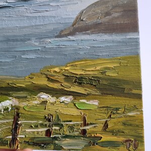 Pode incluir: Pintura a &oacute;leo de uma paisagem costeira, com estilo impasto. A obra retrata um mar, uma fal&eacute;sia rochosa e um primeiro plano gramado. A paleta de cores inclui tons de azul, verde, castanho e cinza.
