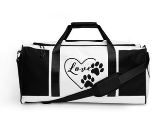 Peut inclure: Sac de voyage en toile blanche et noire avec un cœur noir et un motif d'empreintes de pattes. Le texte "Love" est à l'intérieur du cœur.