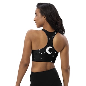 May include: Black sports bra with a white crescent moon and stars print.