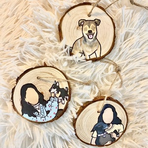 May include: Three round wooden ornaments with painted portraits of people and their pets. The first ornament features a brown and white dog. The second ornament features a person holding a small black and white dog. The third ornament features a person holding a black dog.