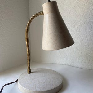 May include: A set of three ceramic mugs with a speckled, matte finish. The mugs are in shades of cream, light brown, and dark brown. Each mug has a simple, minimalist design and a rounded handle.