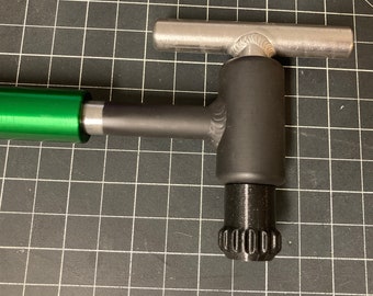 May include: A green and black metal tool with a T-shaped handle and a knurled knob. The tool is designed for tightening and loosening nuts and bolts.