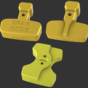 Pode incluir: Três objetos geométricos amarelos são exibidos contra um fundo escuro. Um objeto tem o texto "SPAM CODE". Todos os objetos têm a palavra "suila". Os objetos têm uma base retangular com uma alça.