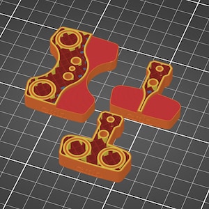 Pu&ograve; includere: Tre pezzi di puzzle rossi e arancioni con intricati disegni circolari e geometrici. I pezzi sono disposti su uno sfondo a griglia grigia, mostrando le loro forme e dettagli unici. I pezzi sembrano essere stampati in 3D.