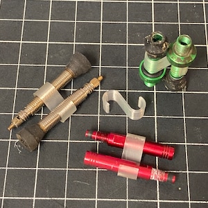 May include: A set of five bicycle valve extenders, including two red, two green, and one silver. The extenders are designed to make it easier to inflate bicycle tires.