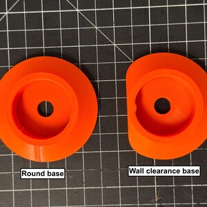 May include: Two orange plastic bases are shown. One is round, and the other has a wall clearance design. Each base has a central hole. The text "Round base" and "Wall clearance base" are below the respective bases.