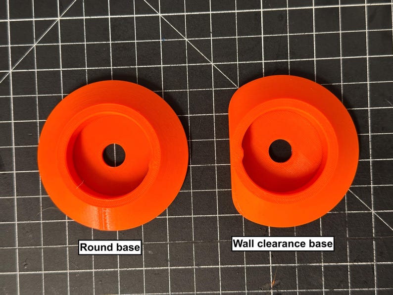May include: Two orange plastic bases are shown. One is round, and the other has a wall clearance design. Each base has a central hole. The text "Round base" and "Wall clearance base" are below the respective bases.