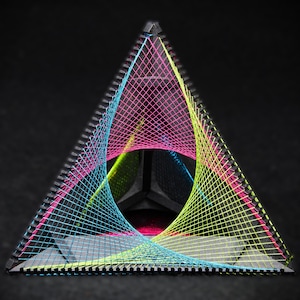 Könnte beinhalten: Eine geometrische Skulptur in Dreiecksform. Der dunkle, graue Rahmen ist mit neonfarbenen, pinkfarbenen, blauen und gelben Fäden gefüllt, die ein farbenfrohes, offenes Design bilden. Der schwarze Hintergrund hebt die leuchtenden Farben hervor.