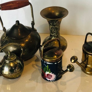 May include: A set of four miniature brass items: a teapot, a vase, and two watering cans. The teapot and vase feature intricate floral designs. One watering can is painted blue with pink flowers, while the other is plain brass.