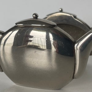 Könnte beinhalten: Ein Set aus zwei silbernen Teekannen-Salz- und Pfefferstreuern. Die Streuer sind aus poliertem Metall und haben ein abgerundetes, modernes Design.