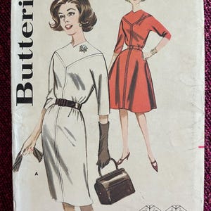 Op de afbeelding: Vintage Butterick naaipatroon envelop met illustraties van twee jurken. De cover toont een witte jurk met een zwarte riem en een rode jurk met een bijpassende riem. De envelop bevat de tekst "BUST 32 SIZE 12 9895 60c".