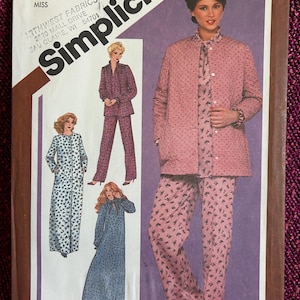 Könnte beinhalten: Simplicity Schnittmuster Nummer 9784 für Größe 12. Das Schnittmuster enthält Anleitungen zum Nähen einer langen Robe, einer kurzen Robe und eines Schlafanzugs mit Jacke und Hose. Das Schnittmuster ist für ein Damenkleidungsstück und hat einen Blumendruck.