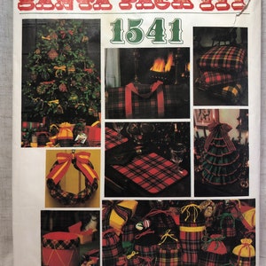 Op de afbeelding: Een vintage Vogue Patterns naaipatroon voor een kerstmanzak, met een rood en groen ruitpatroon. Het patroonnummer is 1541. Het patroon bevat instructies voor het maken van verschillende kerstthema-artikelen, waaronder een kussen, een draagtas, een krans, een boomrok en cadeauzakken.