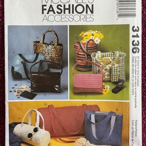 May include: A McCall's Fashion Accessories pattern envelope featuring various handbag designs. The image showcases handbags in diverse styles, including a leopard print tote, a red polka dot bag, and a blue tote bag. The envelope includes the number 3136.