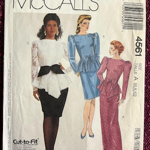 May include: McCall's sewing pattern for a dress, size 6, 8, and 10. The pattern includes three different styles: a white dress with a black sash, a blue dress with a bow, and a pink dress with a bow. The pattern is labeled "Cut-to-Fit" and "Petite-Able".