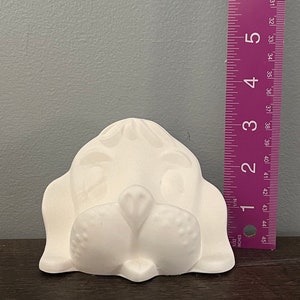 以下が含まれることがあります： テクスチャ加工された表面を持つ白いセラミック製の犬の頭部の置物。置物は約10センチメートルです
