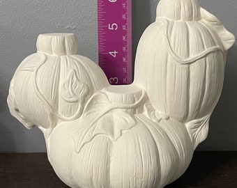 May include: White ceramic pumpkin candle holder with three pumpkins, two smaller pumpkins on top of a larger pumpkin. The pumpkins have a textured surface and a leaf design.