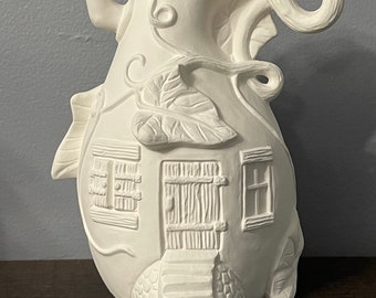 May include: White ceramic gourd-shaped house with a vine and leaf design. The house has a door, two windows, and a small porch with steps. The gourd has a stem with a curled tendril.