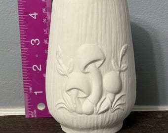 May include: Off-white ceramic vase with a textured surface and embossed mushroom design. The vase is approximately 5 inches tall. The vase has a wide opening and a slightly tapered shape. The vase is suitable for home decor.