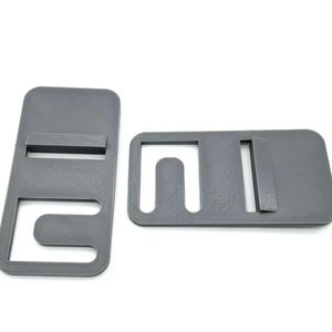 May include: Two gray plastic pieces with cutouts, designed to be used as a strap holder for a bag or backpack.