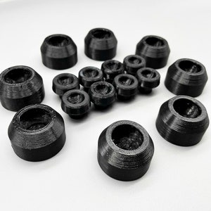 May include: A collection of 15 black plastic furniture feet, some with a larger diameter than others. The feet are designed to protect floors from scratches and wear.