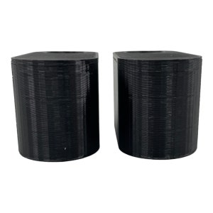 May include: Two black, cylindrical objects with rounded tops and bottoms. The objects are side-by-side, and appear to be 3D-printed. The surface has a textured, layered appearance. The objects are set against a white background.