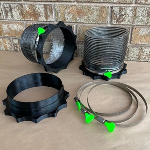 May include: Four black and silver duct connectors with green adjustable clamps. The connectors are made of a flexible material and have a ribbed design. The clamps are used to secure the connectors to other parts of a ventilation system.