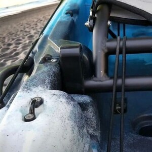 May include: Close-up of a blue and white kayak with black metal frame and hardware. The kayak has a speckled pattern and a black metal frame with attached ropes. A metal hook is visible on the kayak's surface.